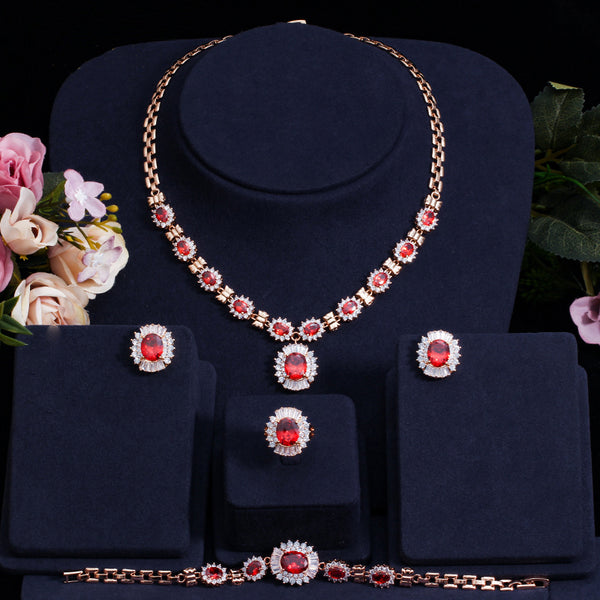 Conjunto de 4 piezas de joyería con collar, pulsera, pendientes y anillo de circonita cúbica roja en color dorado.