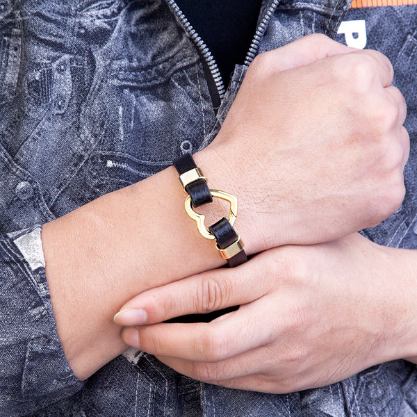 Pulsera de mujer moderna con cierre de resorte en forma de corazón, de metal dorado y cuero negro.