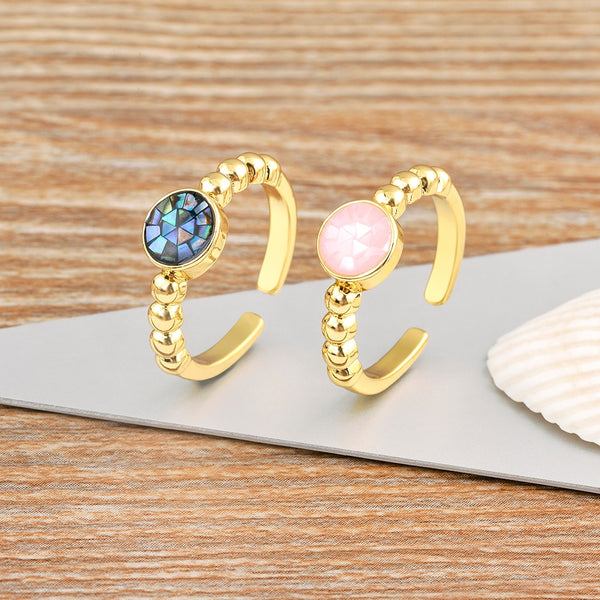 Anillo abierto ajustable con concha natural redonda bañada en oro.