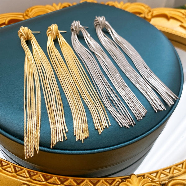 Pendientes largos metálicos con borlas y nudo de moda en color dorado y plateado.