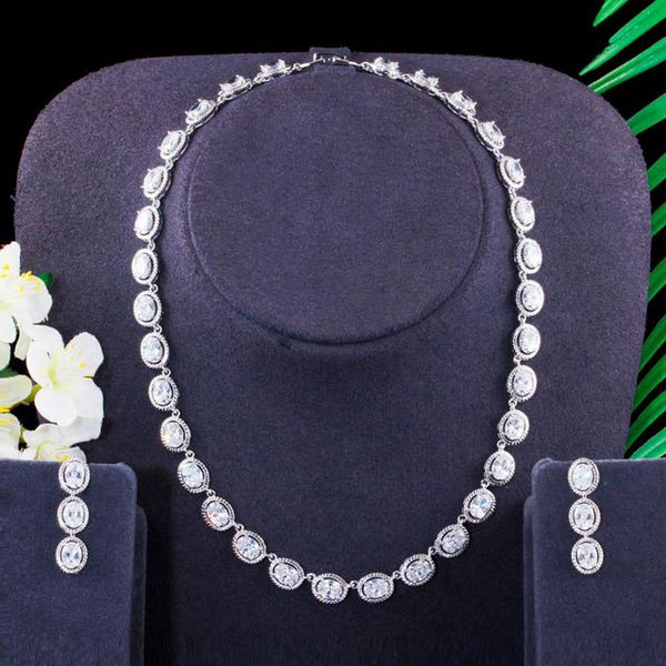 Conjunto de joyería con gargantilla, collar y pendientes de circonita cúbica brillante en color plateado y redondo.