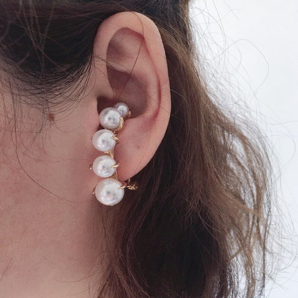 Un par de elegantes pendientes brincos de perlas de color dorado