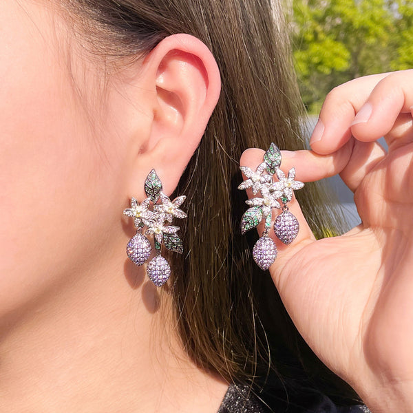 Pendientes largos colgantes de circonita cúbica con flor blanca y racimo morado.