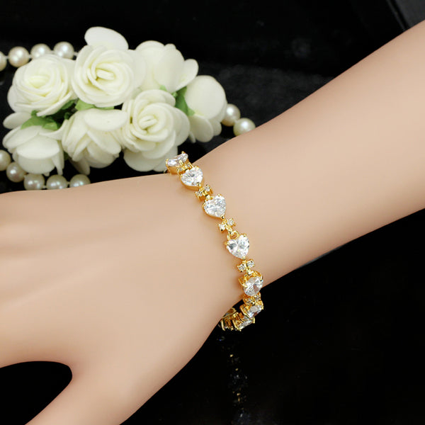 Pulseras de boda románticas con forma de corazón grande y circonitas cúbicas conectadas en color dorado.