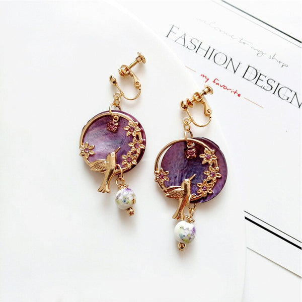 Pendientes vintage de cuentas de concha morada con clip de flores y pájaros en color dorado.